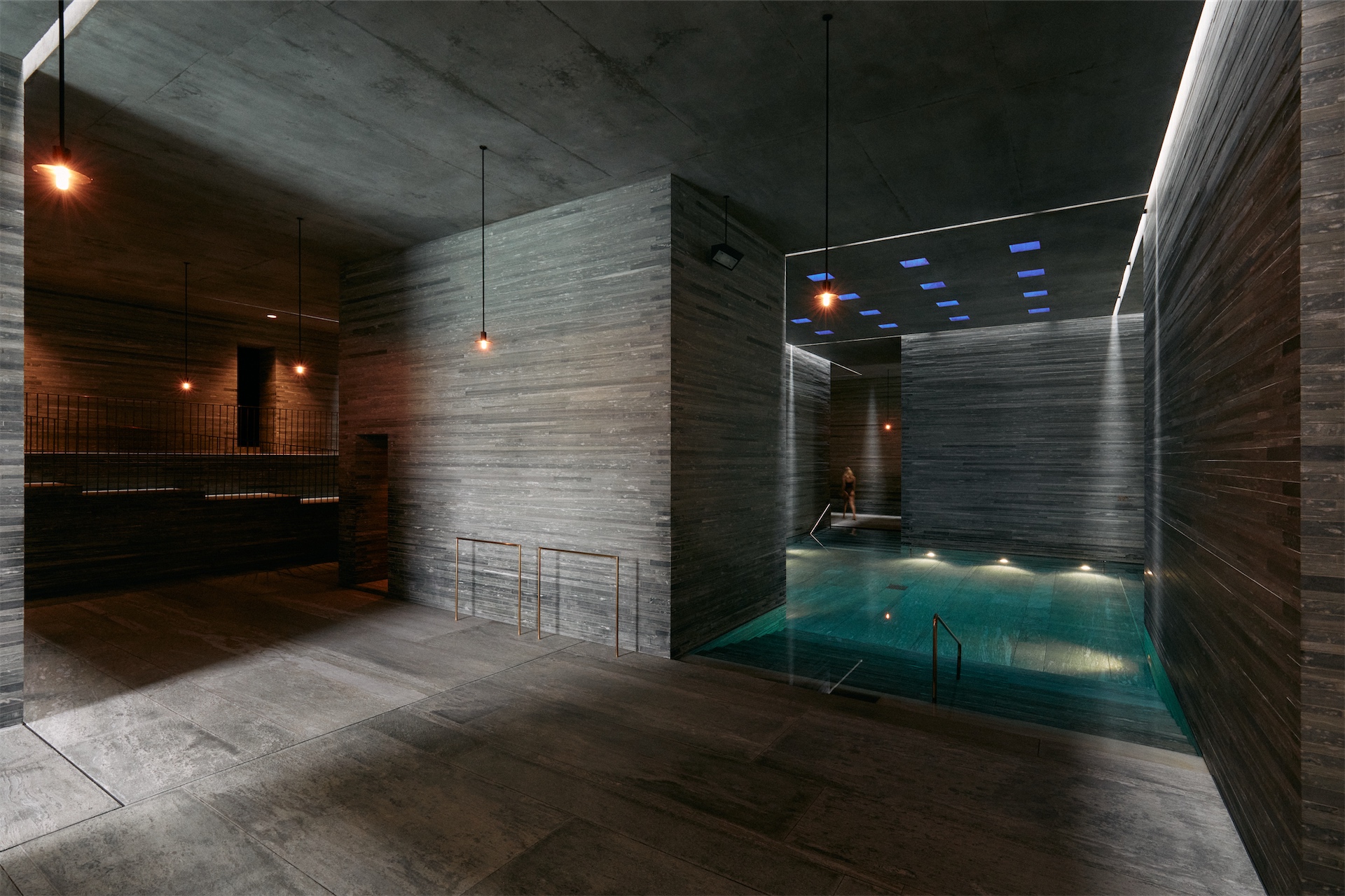 Indoor thermal pool at 7132 Therme in Vals, Switzerland, surrounded by stone walls and soft lighting.
