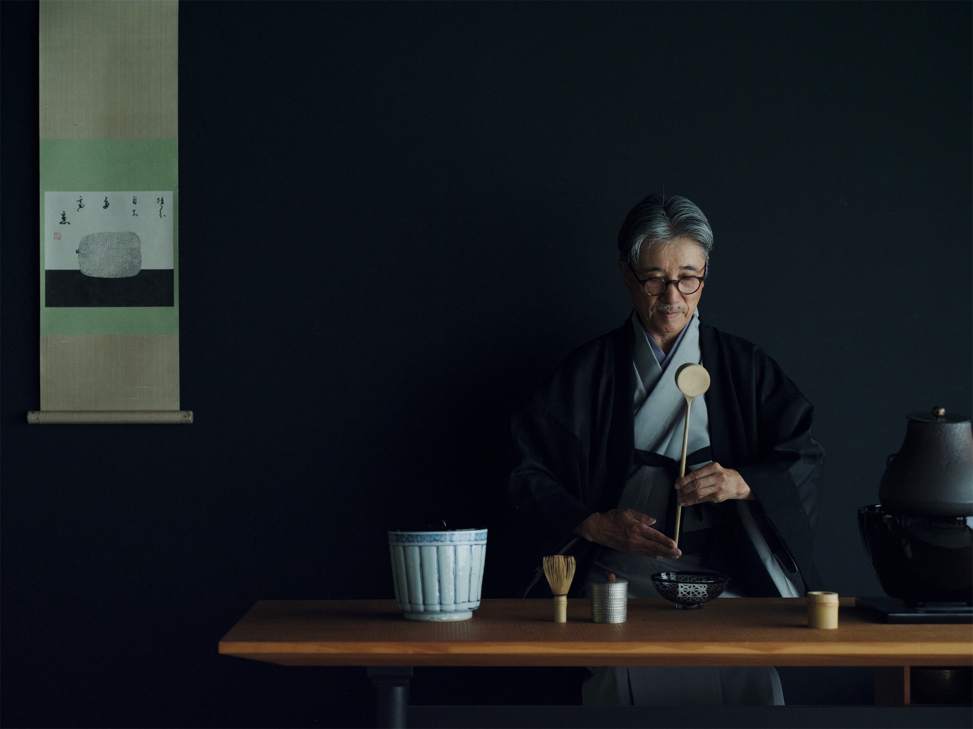 Tea ceremony at Beniya Mukayu, with a tea master performing precise movements in a dimly lit room.