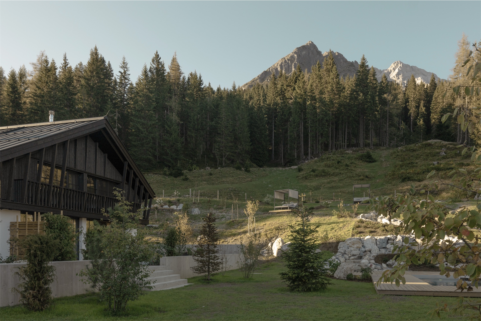 Summer view of Birgkar set within green alpine meadows, forested slopes, and rocky mountain peaks.