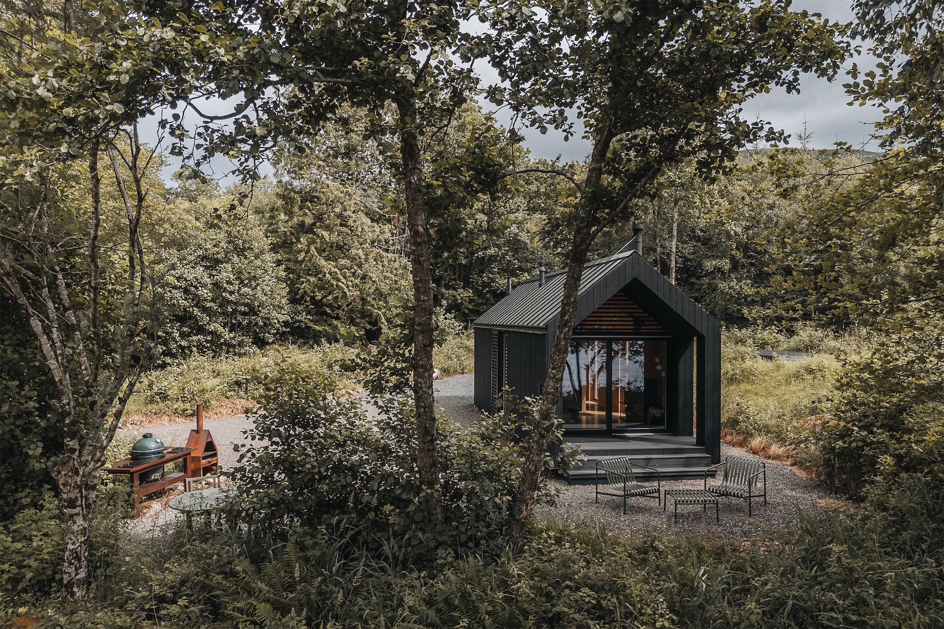 Kabn cabin surrounded by trees and outdoor seating area.
