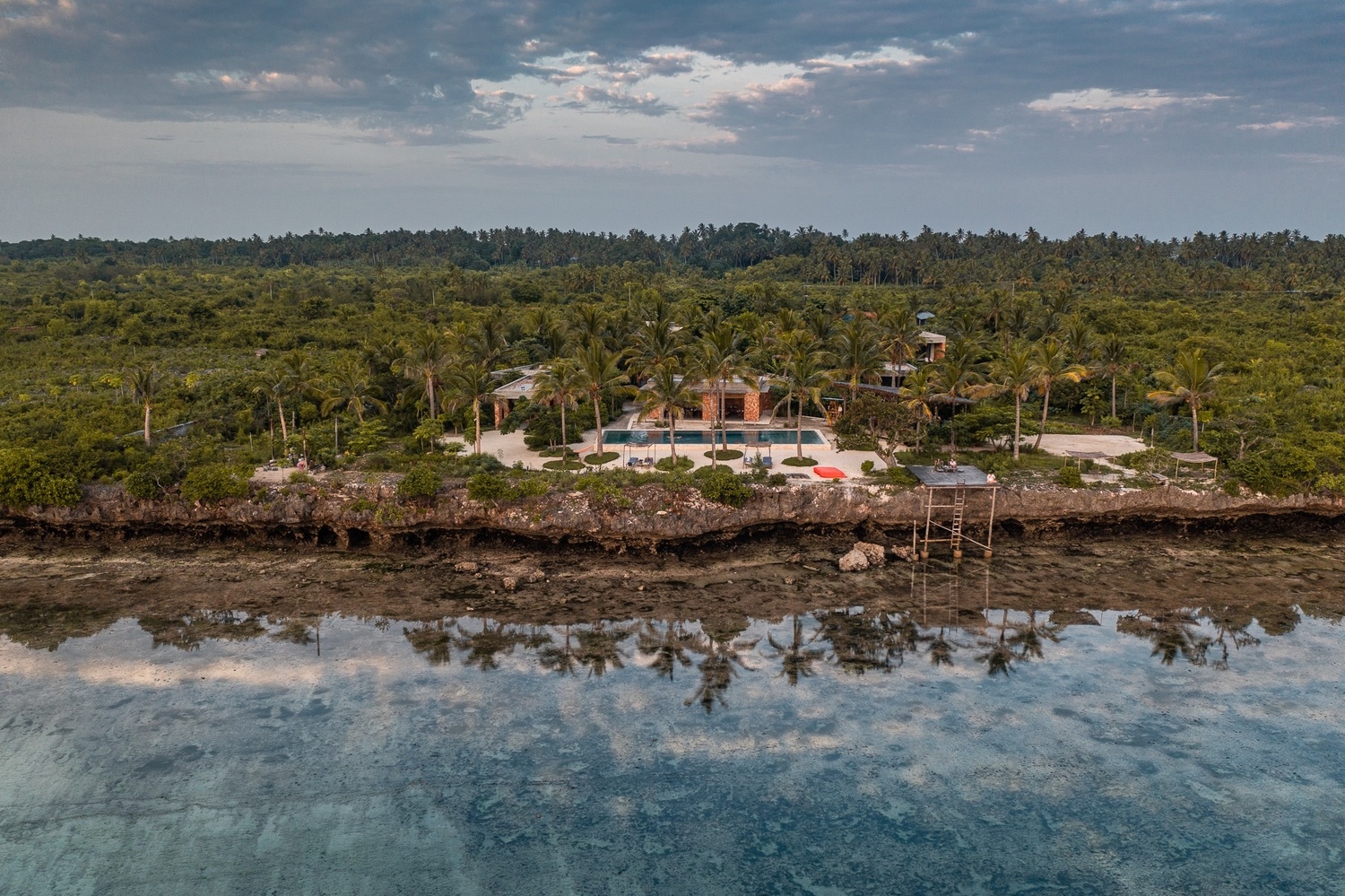 Aerial view of Kizikula set along a rugged tropical coastline.
