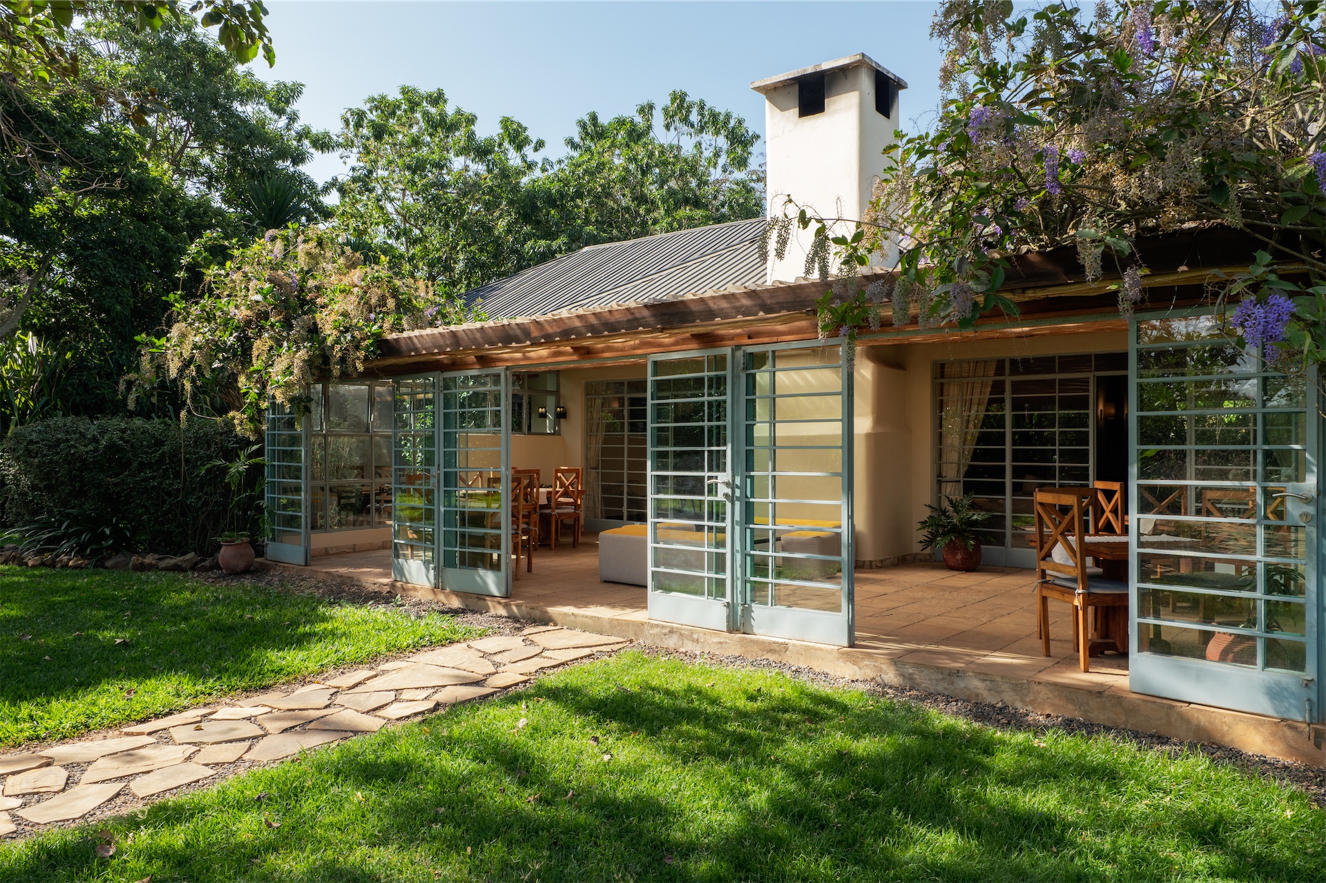 Open glass doors leading to a shaded veranda and garden at Katambuga House.