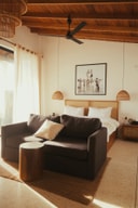 Suite interior at Abode by the Beach with sofa, bed, and natural wood finishes.