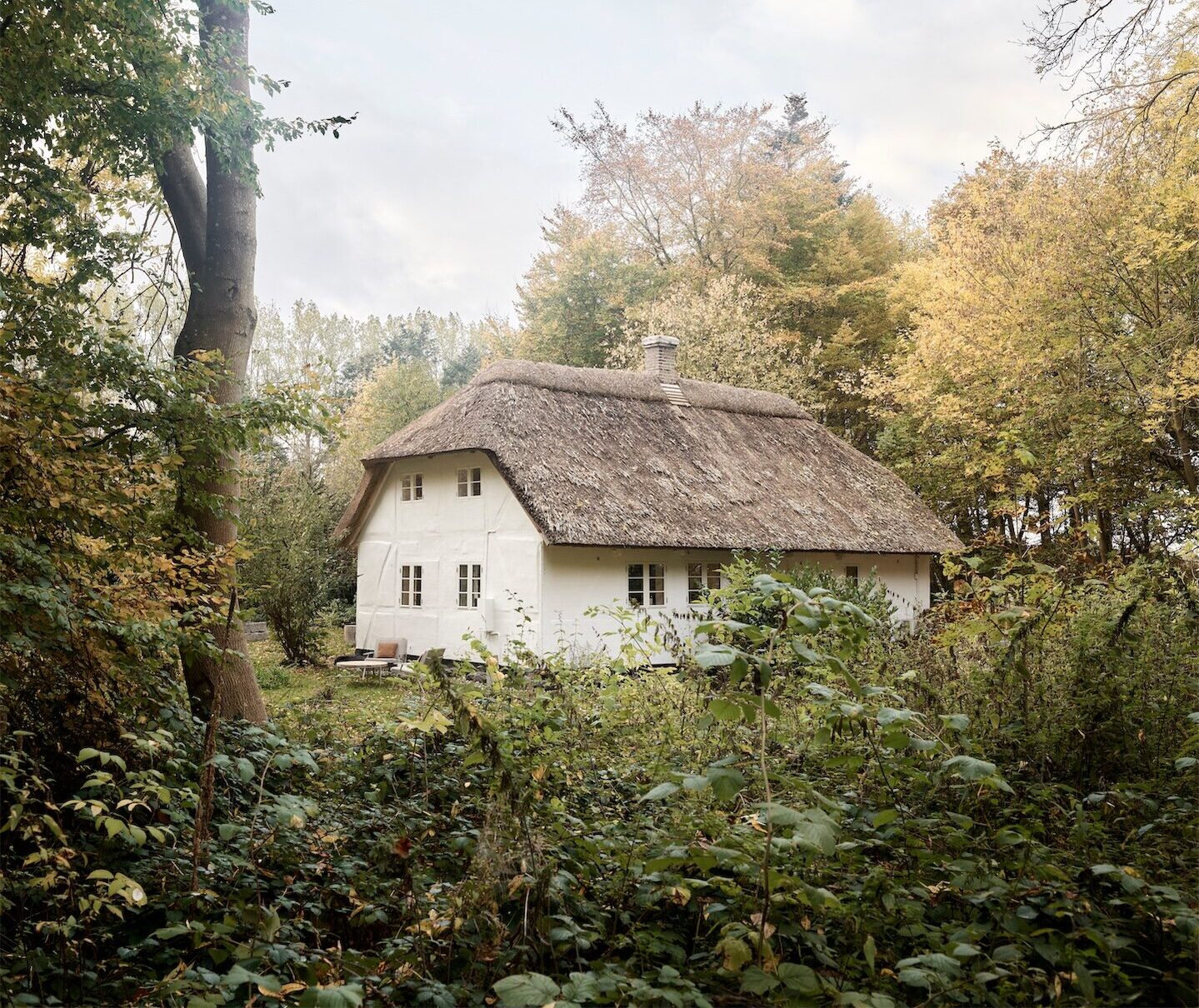 White farmhouse cottage with traditional thatched roof at Vipp Farmhouse.