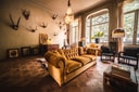 Living room at Boulevard Leopold with velvet sofas, parquet flooring, mounted objects on the walls, a fireplace, and tall windows.