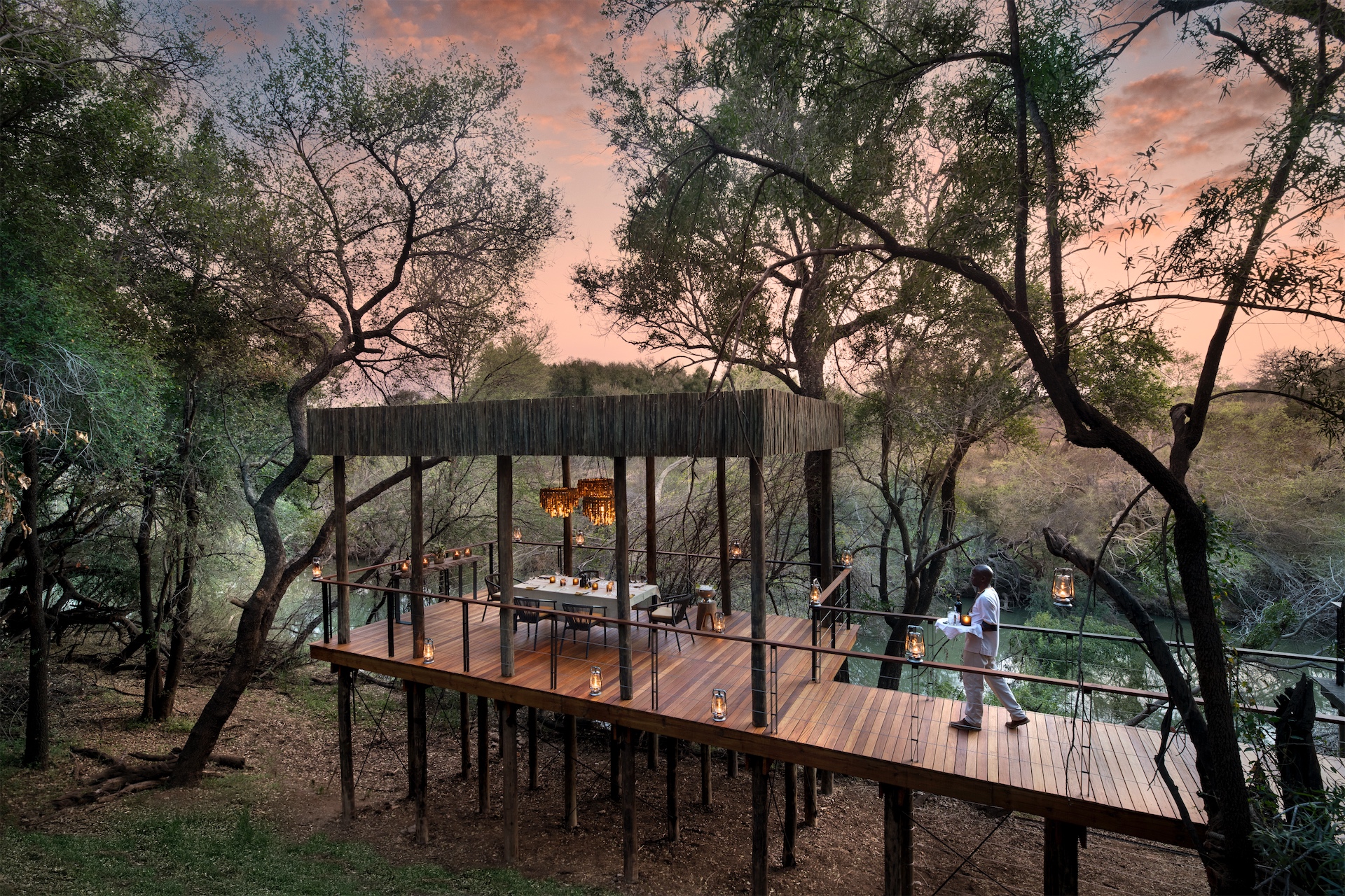 Elevated sala with dining table overlooking the river at Morukuru River House.