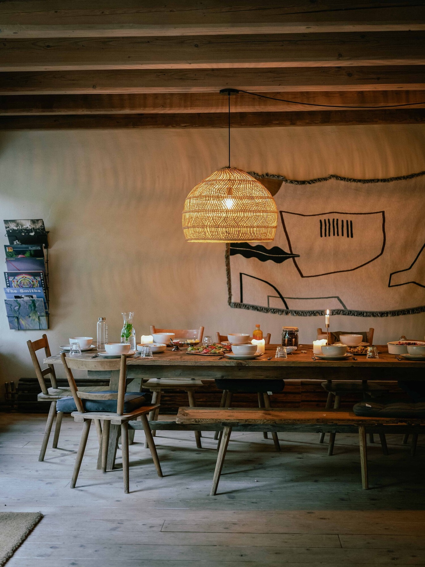 A long communal dining table is set beneath woven pendant lights at Rosso House & Farm. Photography courtesy of Rosso House & Farm.