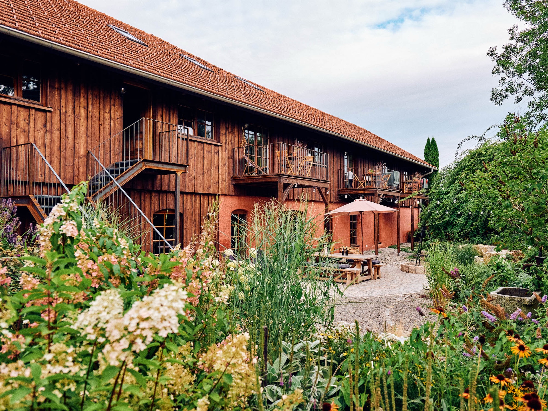 Garden courtyard with flowers, outdoor seating, and wooden balconies at Rosso House & Farm.