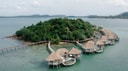 Aerial view of overwater villas connected by curved wooden boardwalk at Song Saa Private Island in Cambodia.