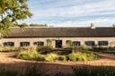 Thatched farmhouse exterior with green shutters and circular garden fountain at Sterrekopje Farm.