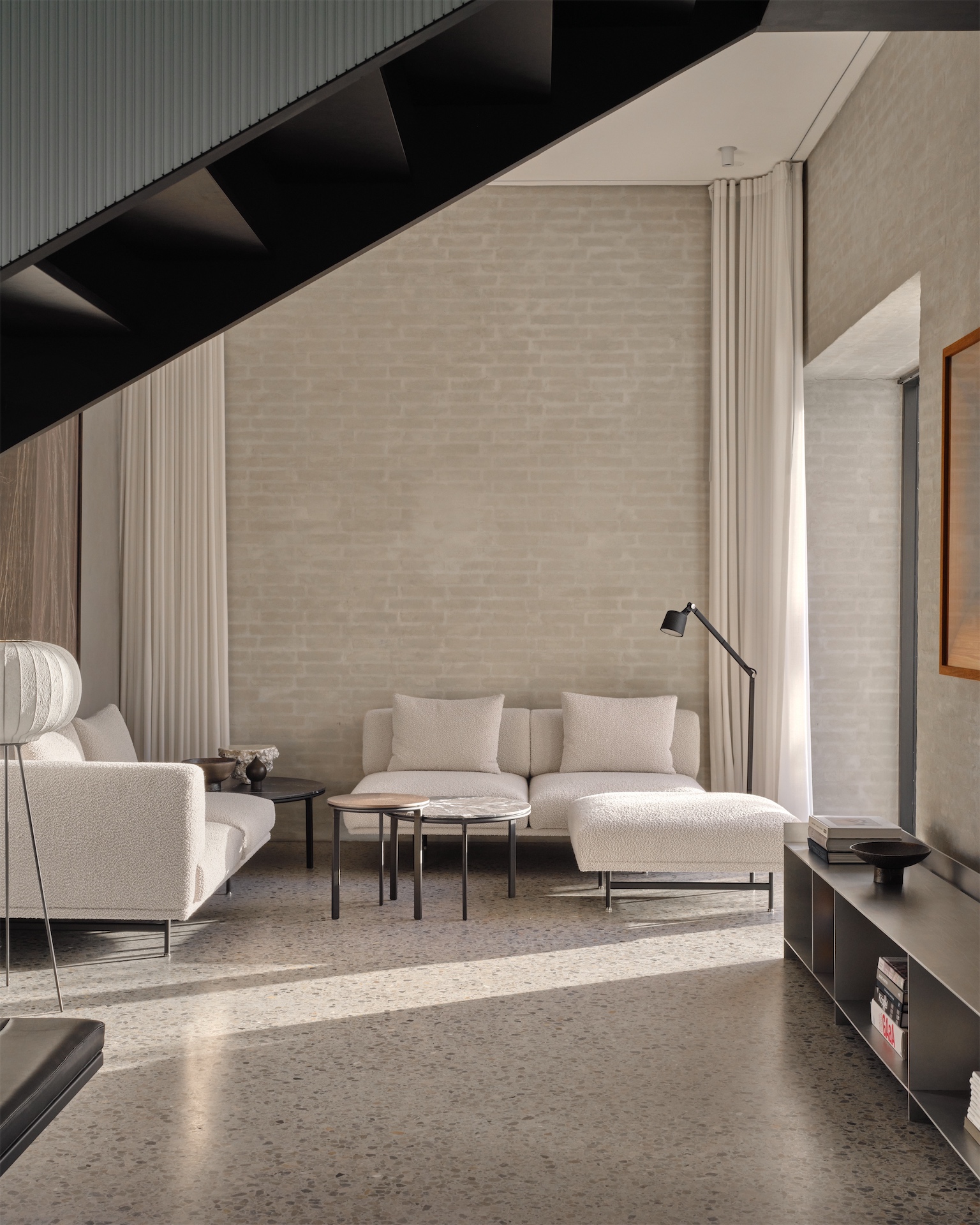 Living room with modular cream sofa and terrazzo flooring at Vipp Chimney House.