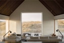 Living room with panoramic window overlooking dunes at Vipp Cold Hawaii.