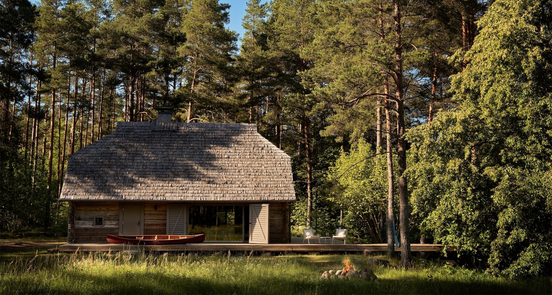 Exterior view of timber cabin surrounded by pine forest at Vipp Salaca River.