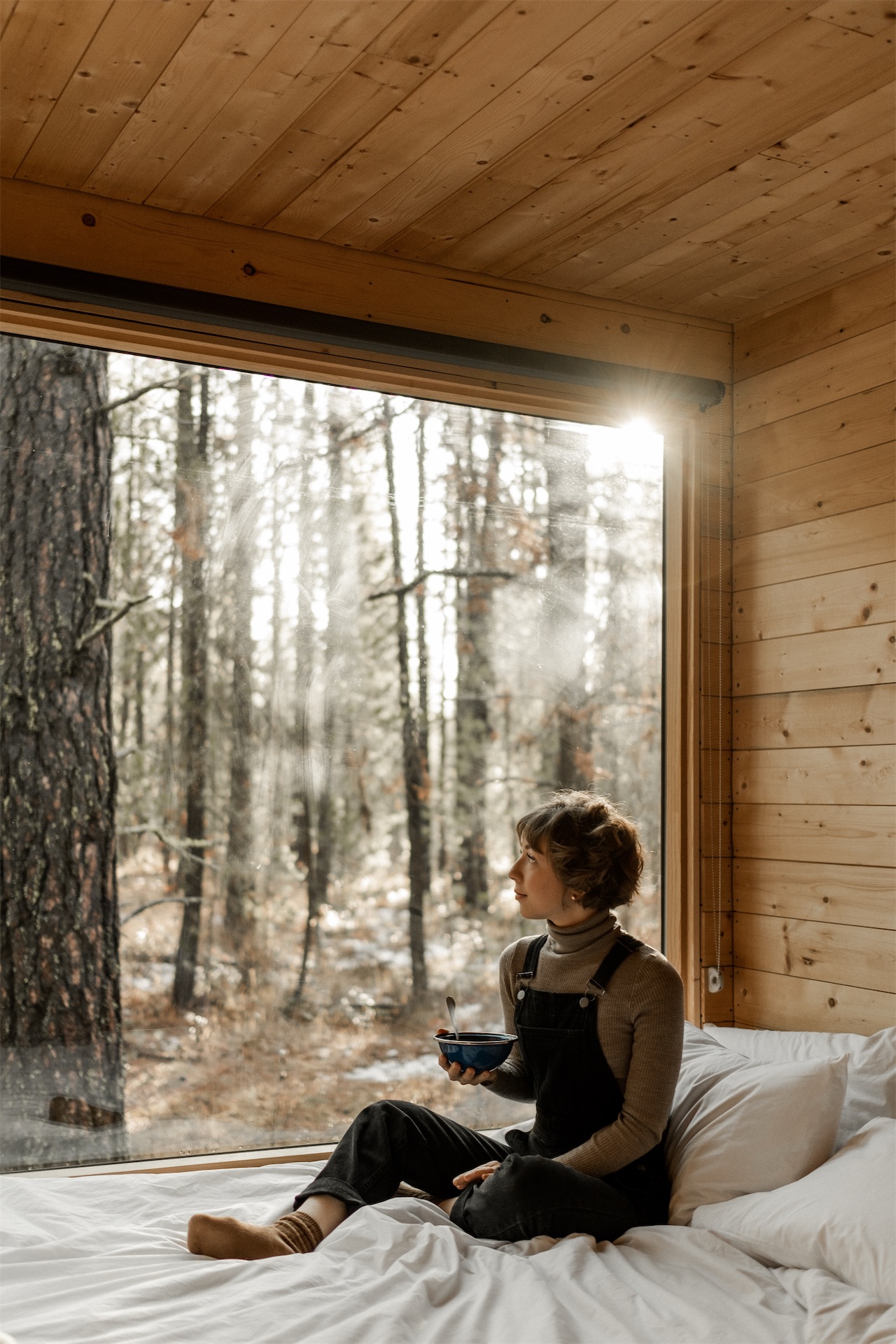 https://cms.here-away.com/wp-content/uploads/2026/04/postcard-cabins-woman-window-forest-morning.jpg